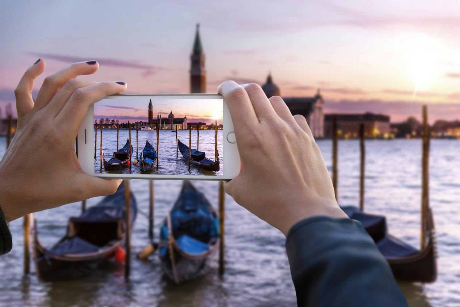 Kvinde med smartphone tager billede af gondoler i Venedig